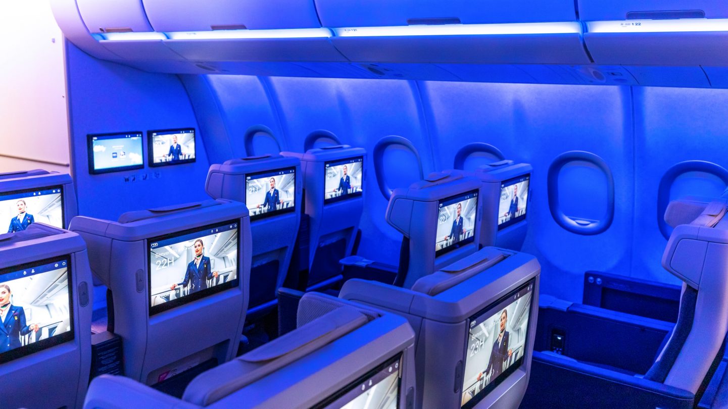 Premium Economy-Sitzplätze mit eingeschalteten Bildschirmen in den Kopfstützen.
