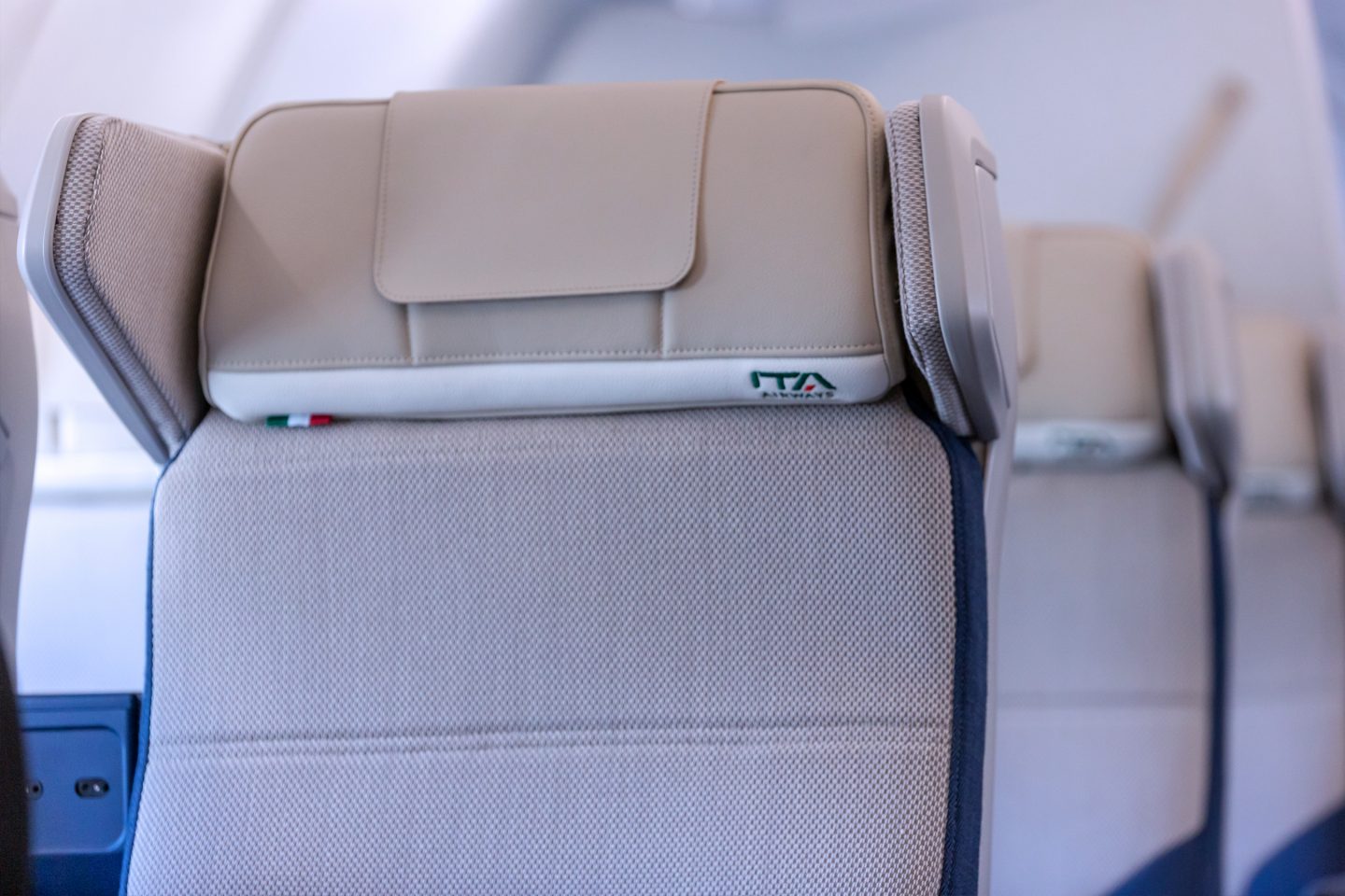 Κοντινό του προσκέφαλου Premium Economy με κέντημα της ITA Airways και την ιταλική σημαία.