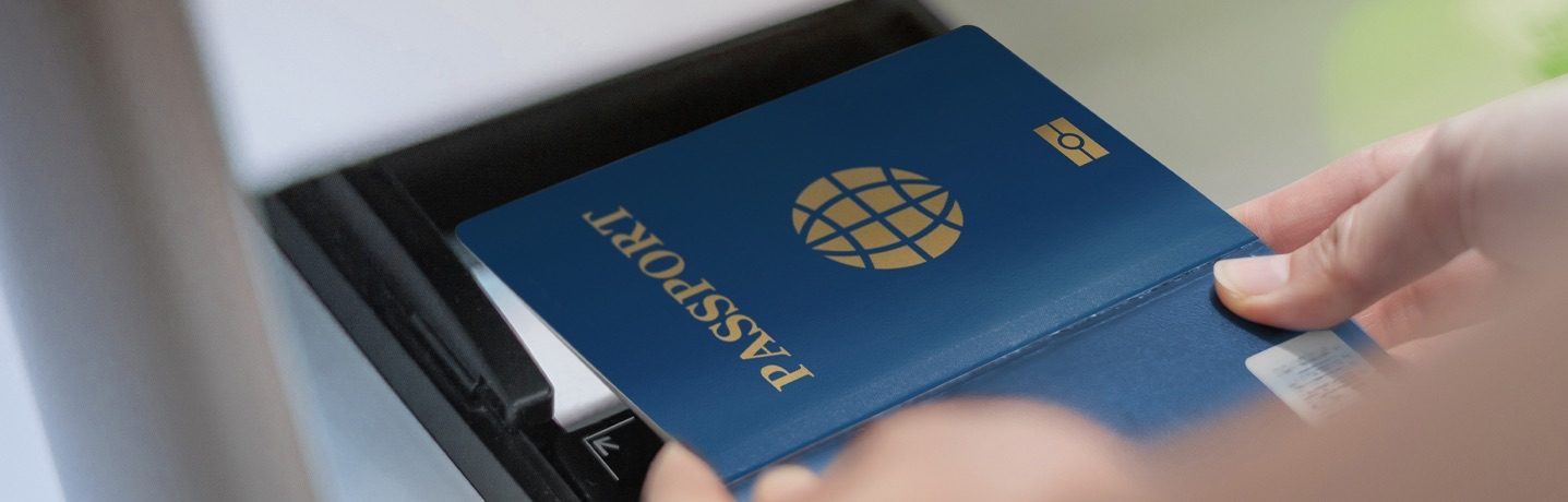 Un pasaporte azul colocado sobre un escáner y sostenido con las manos.