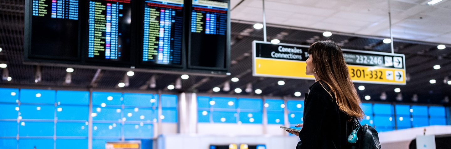 Una mujer de pie comprobando los horarios de vuelo en un aeropuerto.