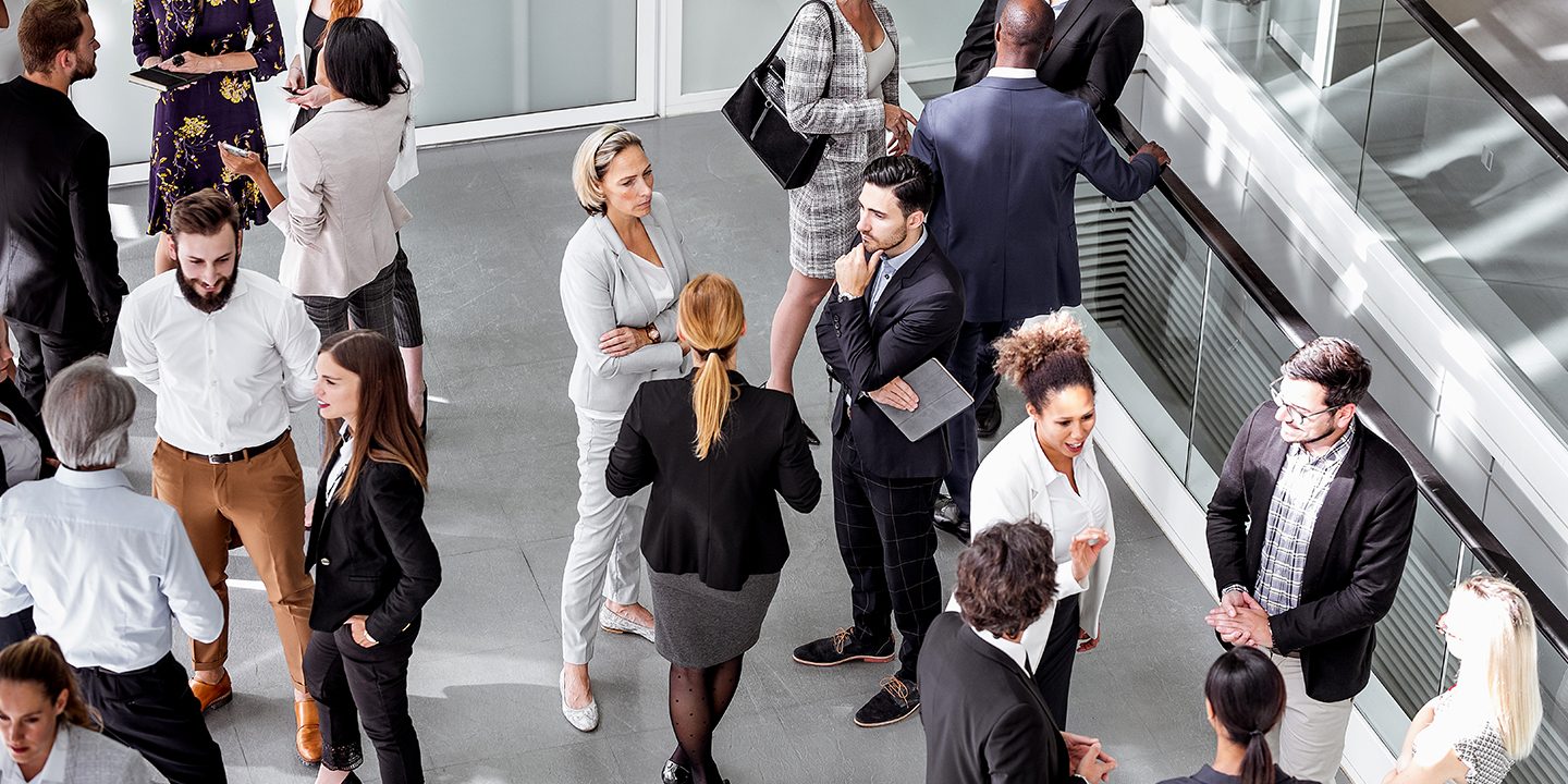 A group of professionals talking in the lobby of a modern office building.