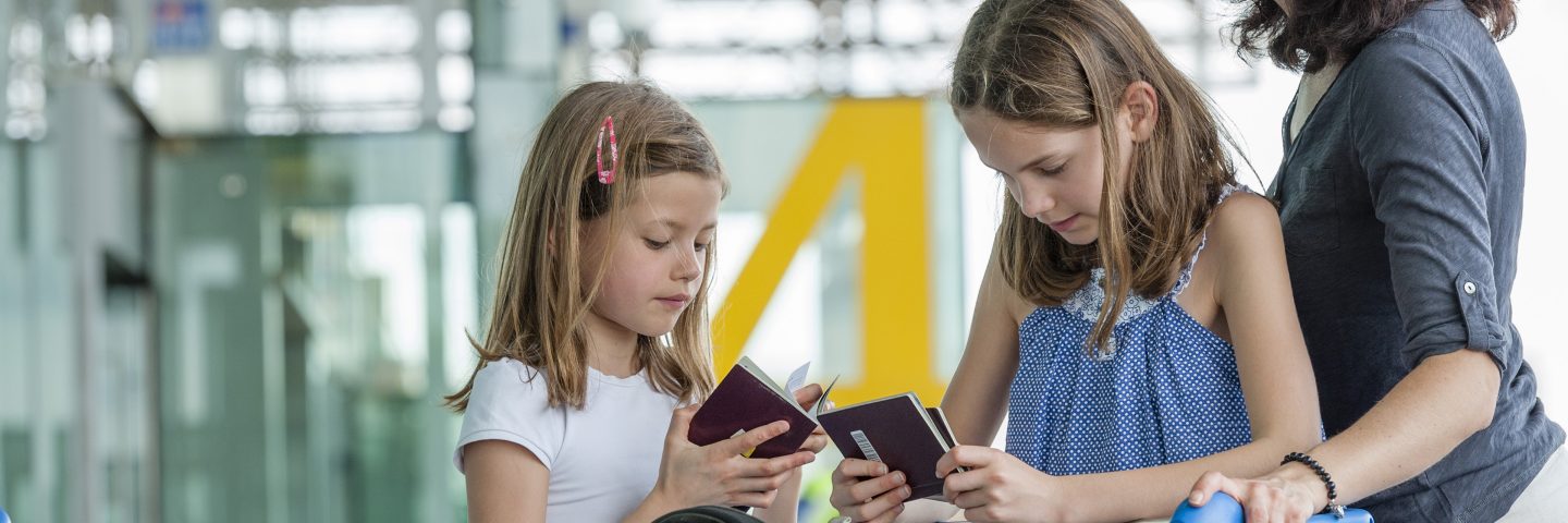 Two children and a woman at the airport holding travel documents.