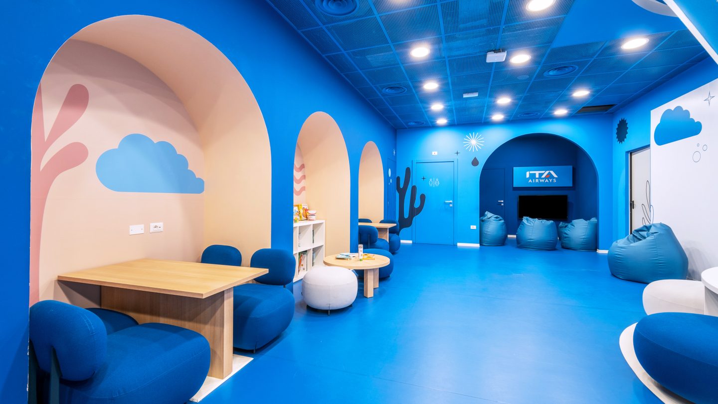 Salon bleu avec niches murales voûtées, sièges et petites tables.