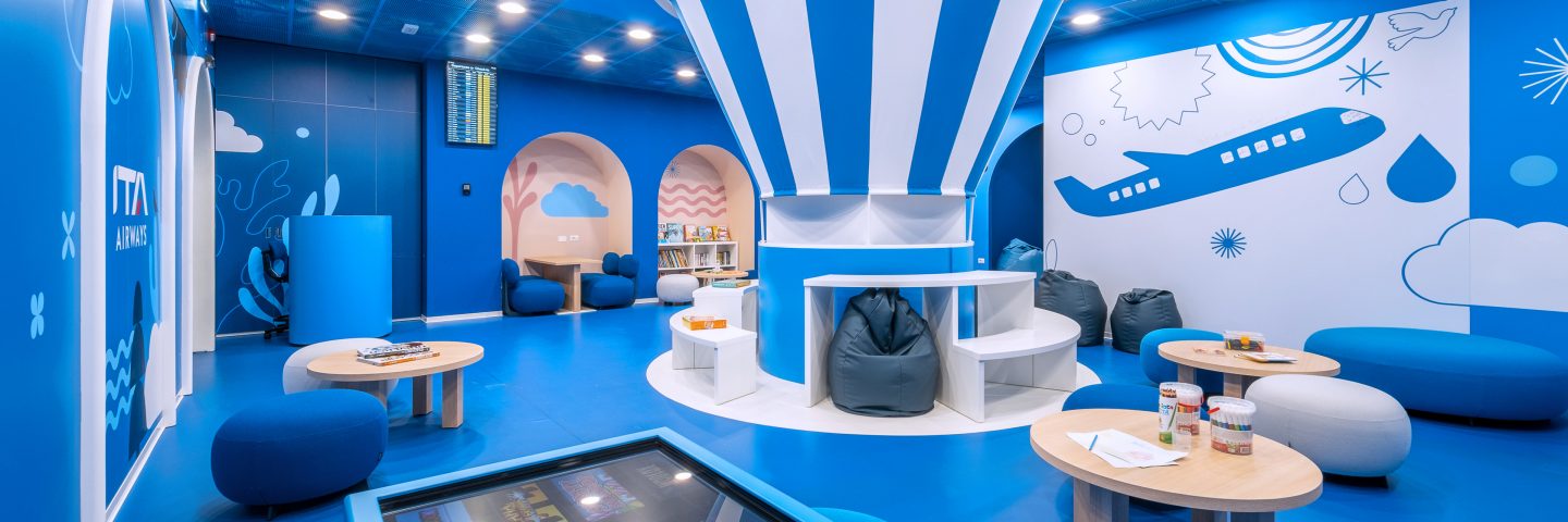 Aire de jeux à l’intérieur du salon Fantasia pour enfants, avec des sièges et des tables.