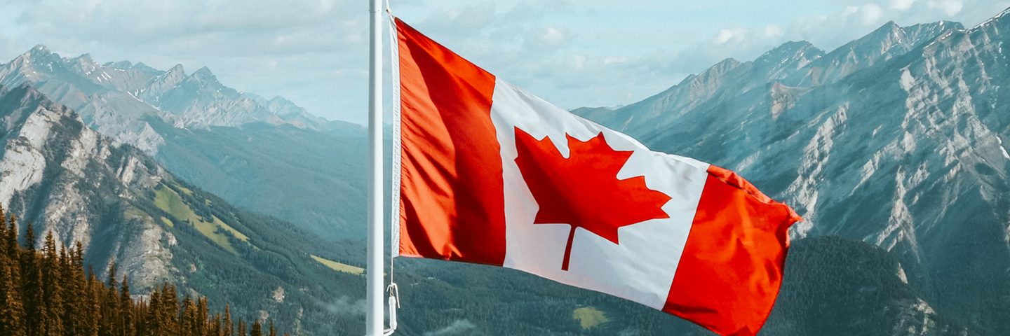 A Canadian flag flying in front of a mountain landscape.