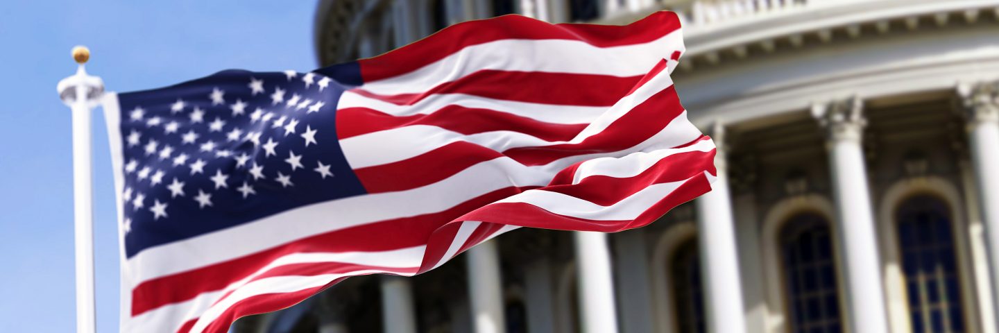 Le drapeau des États-Unis flotte devant un édifice gouvernemental.