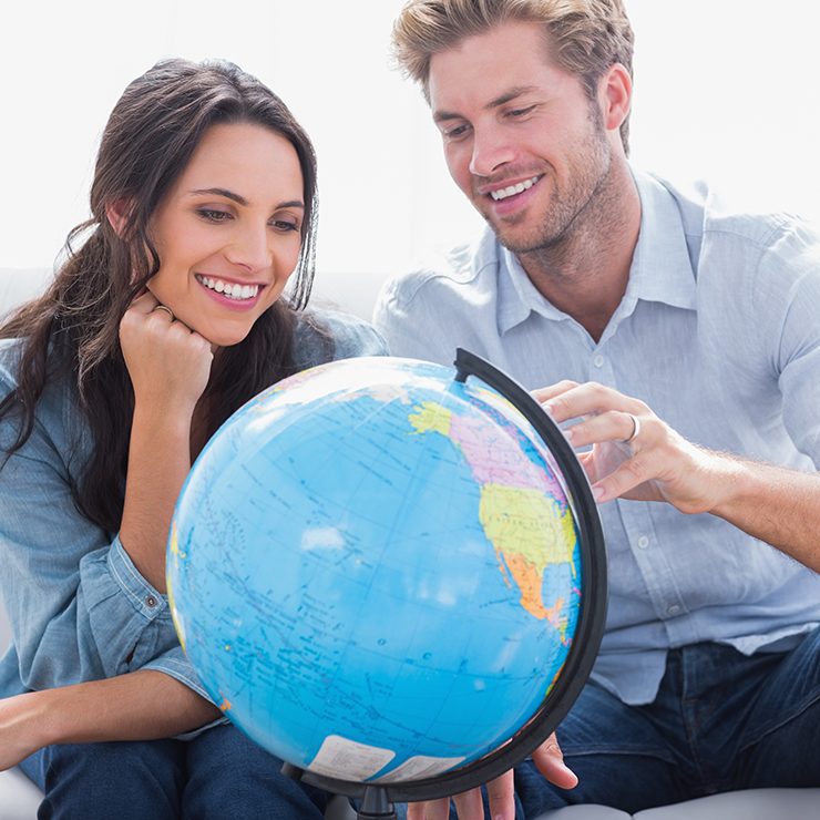 Smiling couple looking at a globe.