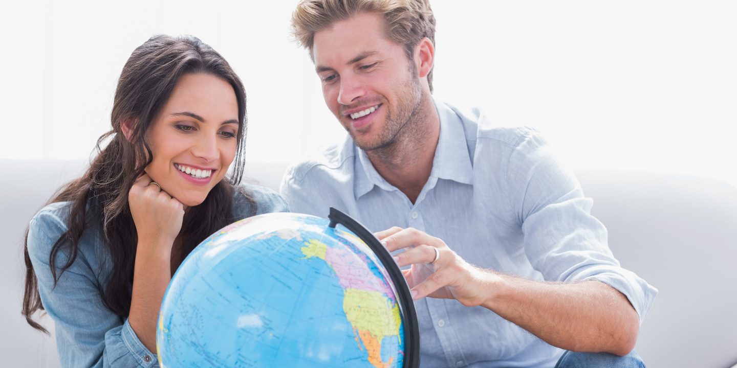 Two people seated looking at a globe and smiling.