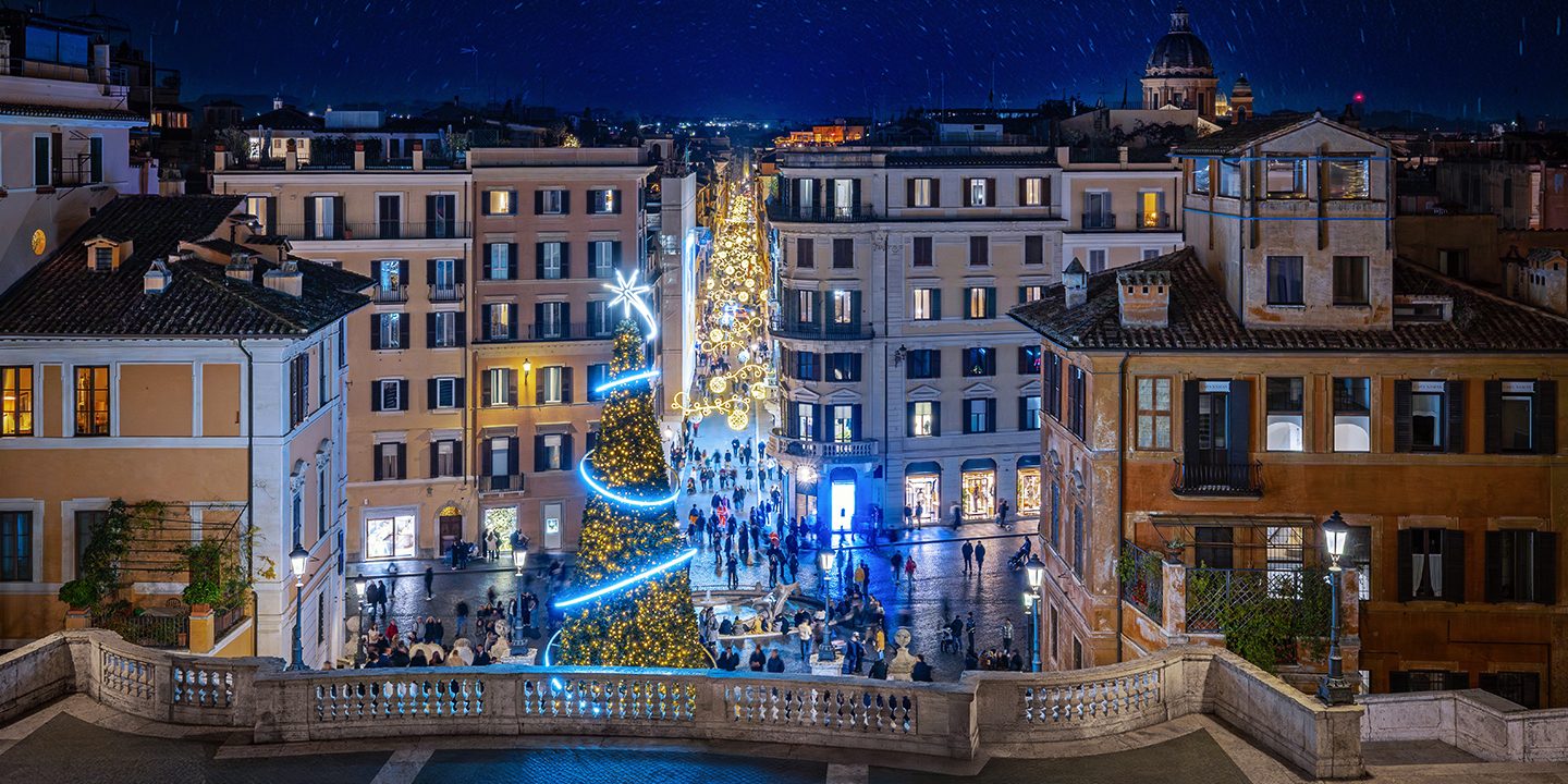 Nächtliche Ansicht eines Platzes in Rom, der von Weihnachtslichtern erleuchtet wird.