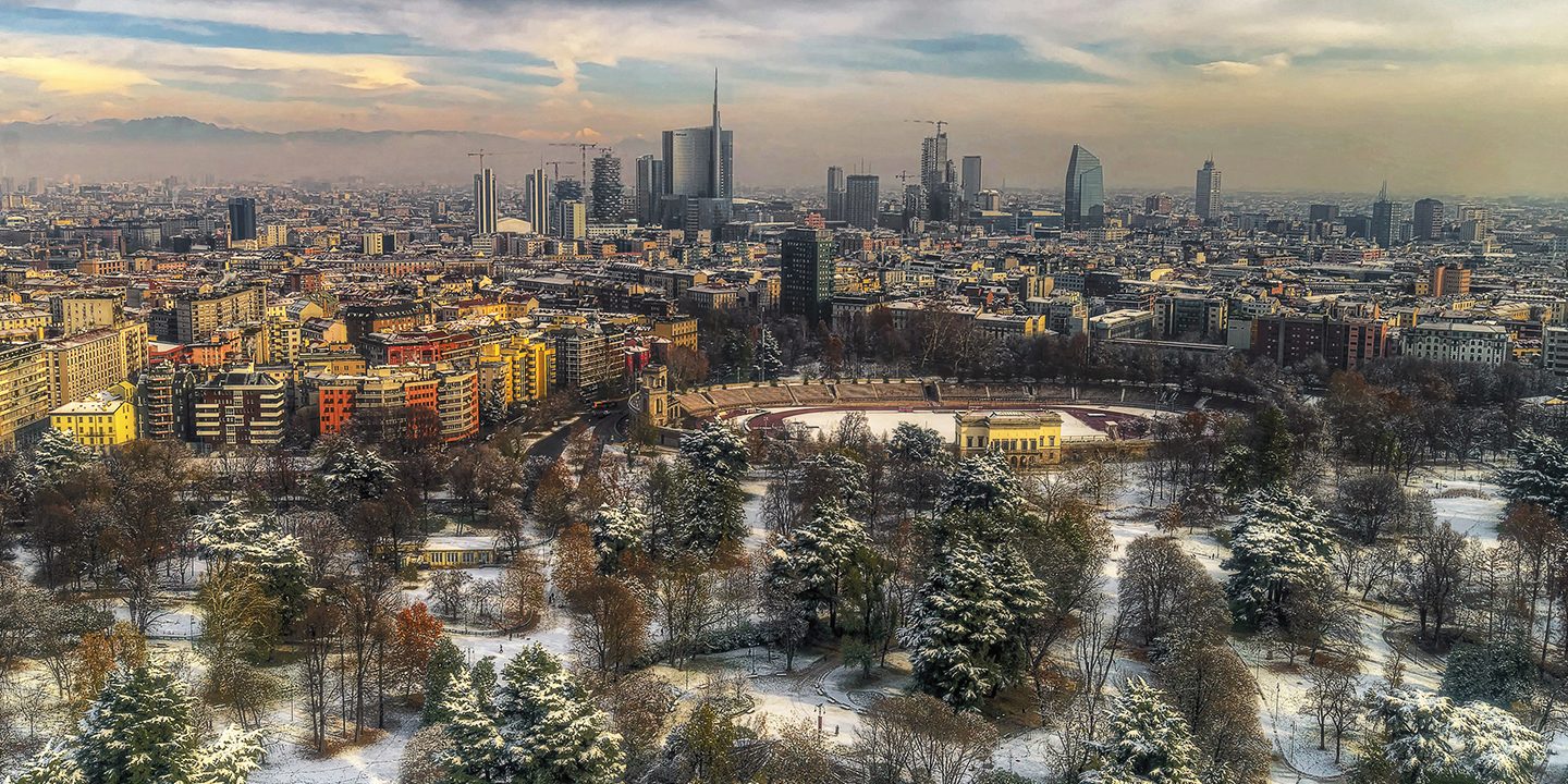 Snowy park with Milan skyline and modern skyscrapers.
