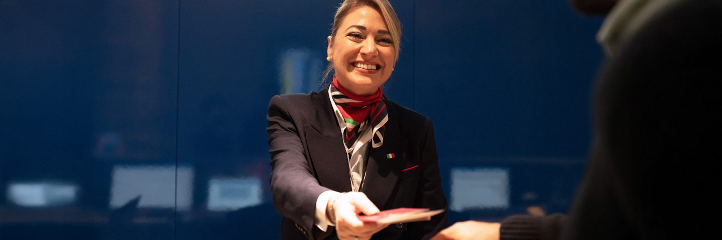Ein Check-in-Agent reicht einem Passagier ein Dokument.