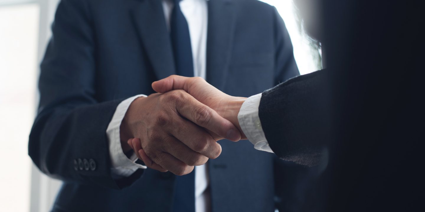 Two people in business attire shaking hands.