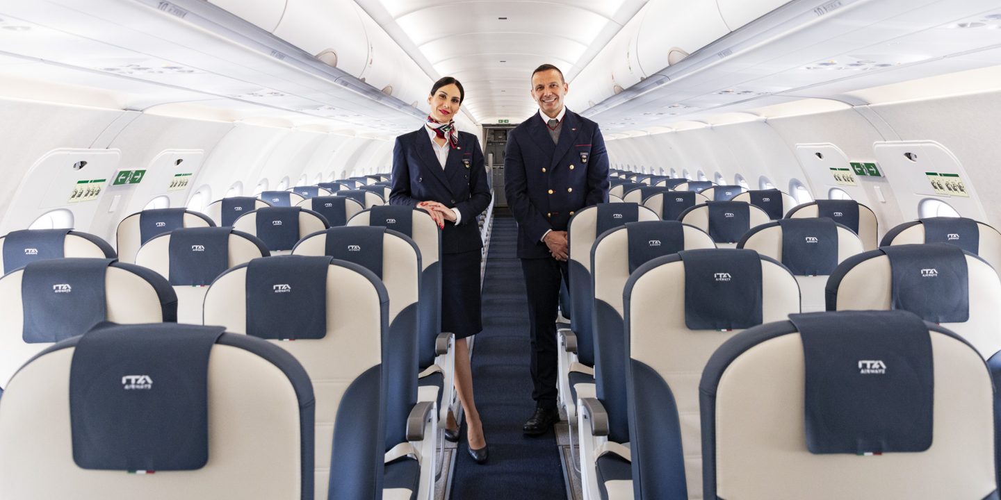 Deux membres de l’équipage d’ITA Airways debout dans l’allée d’un avion.