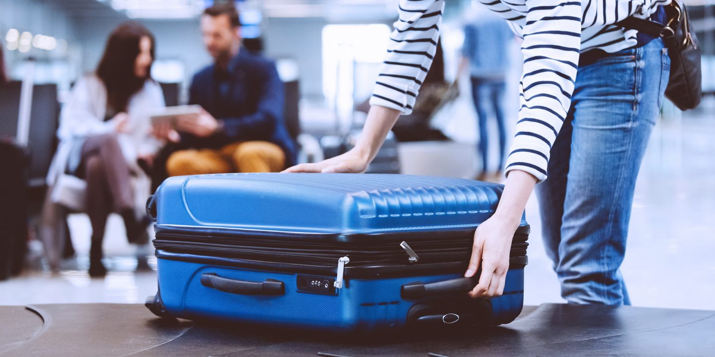 A young passenger collecting her luggage from the baggage carousel.