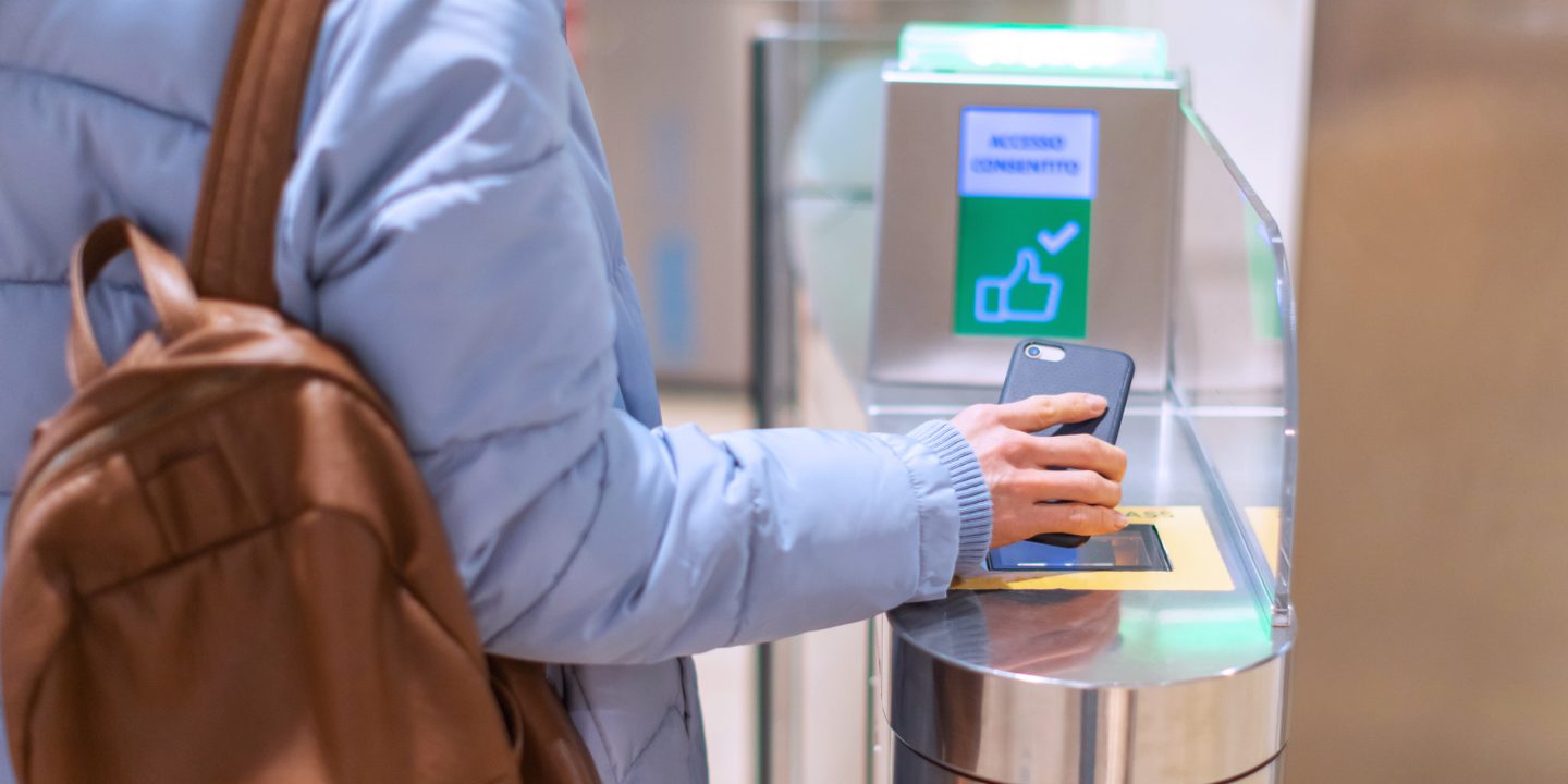 Passenger using a digital boarding pass on a smartphone at an electronic gate.
