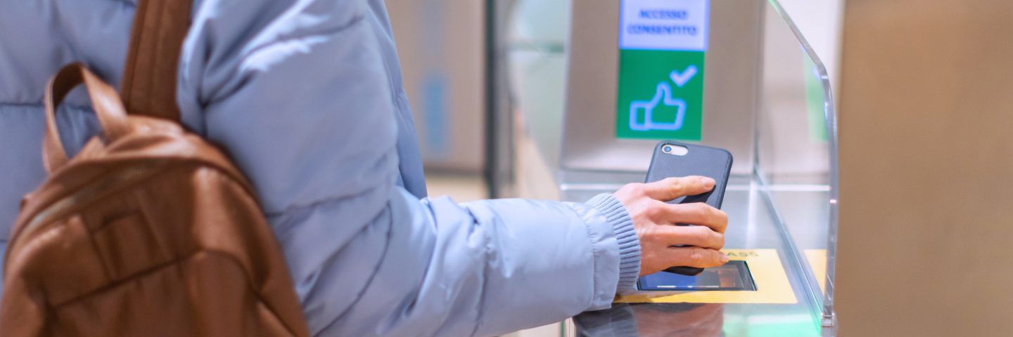 Passenger using a digital boarding pass on a smartphone at an automated gate.
