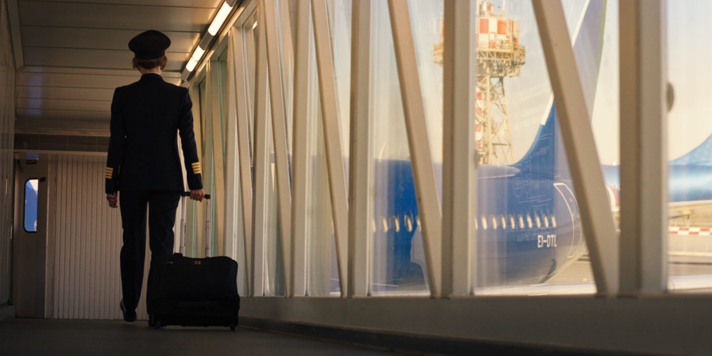Ein Besatzungsmitglied geht mit einem Trolley durch einen Flughafen.