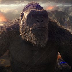 King Kong olhando para cima com uma expressão séria contra uma paisagem esfumaçada.