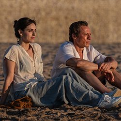 Um homem e uma mulher sentados em uma praia de areia sob a luz quente do sol.