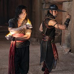 Liu Kang usando magia do fogo ao lado de Kung Lao com um chapéu de abas largas
