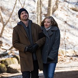Aaron Paul e Amanda Seyfried caminham de braços dados usando casacos de inverno.