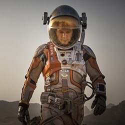 Matt Damon em um traje espacial detalhado caminhando em uma paisagem marciana árida.