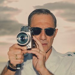 Homem com óculos de sol filmando diretamente com uma câmera de vídeo vintage.