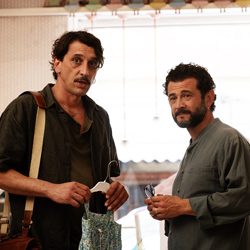 Dois homens de meia-idade juntos dentro de uma loja de roupas.
