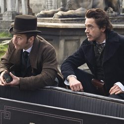 Sherlock Holmes e Dr. Watson agachados juntos dentro de uma carruagem.