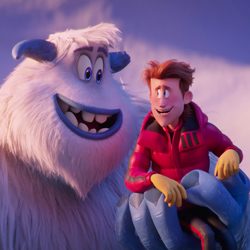 Yeti branco amigável segurando na mão um homem de jaqueta vermelha.