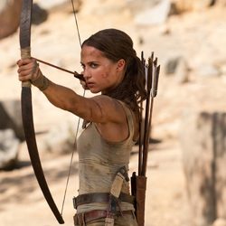 Lara Croft apontando arco e flecha ao ar livre com uma expressão focada.