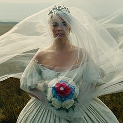Margot Robbie como noiva em um vestido com véu esvoaçante.