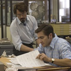 Dois homens em um escritório olhando juntos para uma folha de papel.