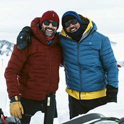 Will Smith e outro homem sorriem com roupas pesadas de inverno na neve.