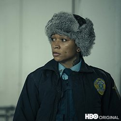 Mulher com uniforme policial azul e chapéu cinza-claro.