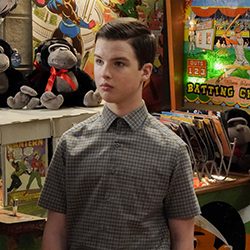 Menino de camisa xadrez em pé em uma colorida loja de quadrinhos.
