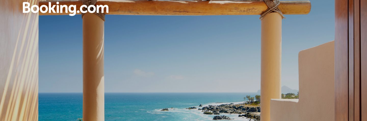 View from a terrace with a pool overlooking a rocky coastline and the blue ocean under a clear sky.