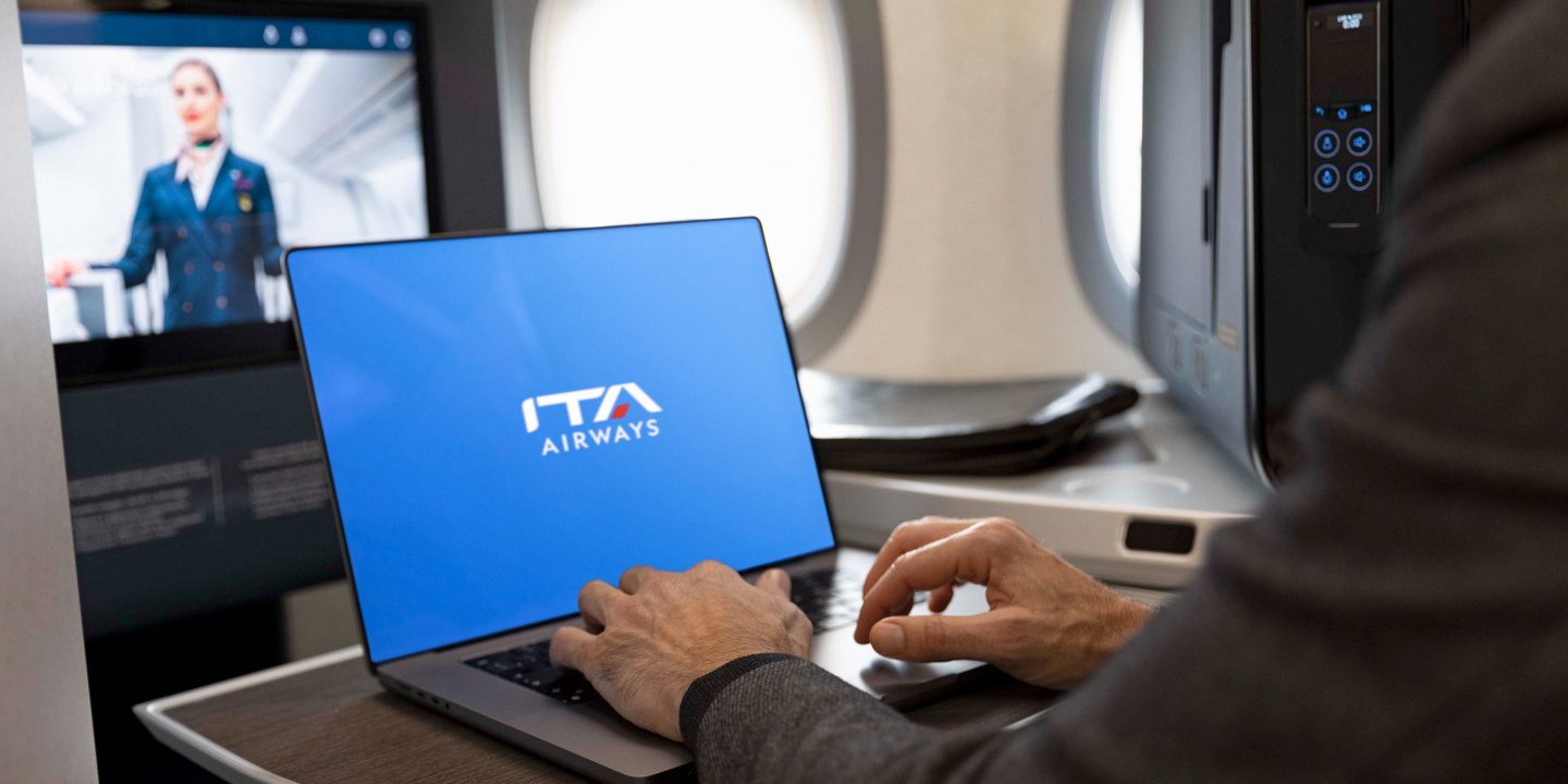 Nahaufnahme einer Person, die auf einem Laptop tippt; auf dem Bildschirm ist das Logo von ITA Airways auf blauem Hintergrund zu sehen
