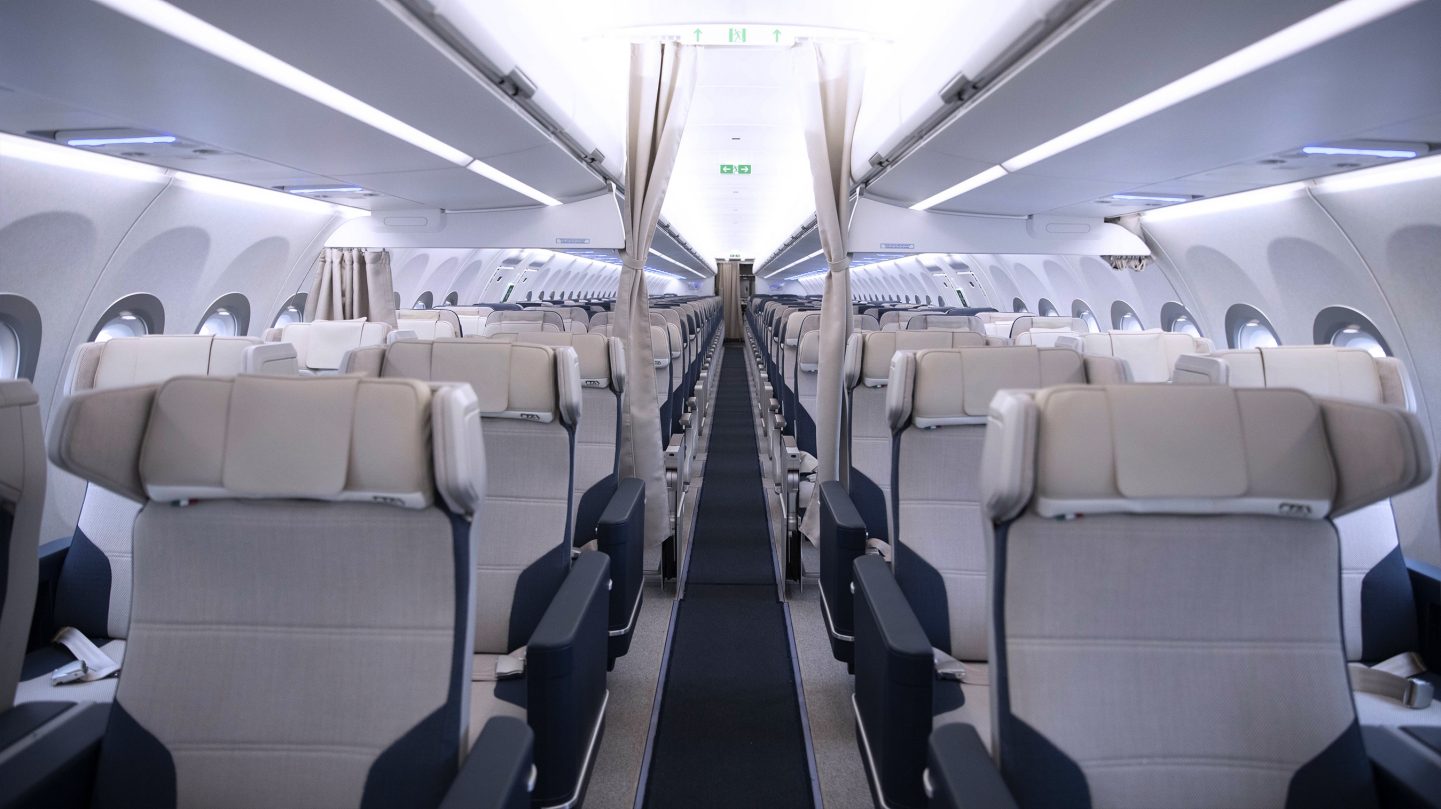 Het gangpad van het vliegtuig met de gordijnen open en zicht op Premium Economy-class en de rest van de cabine.