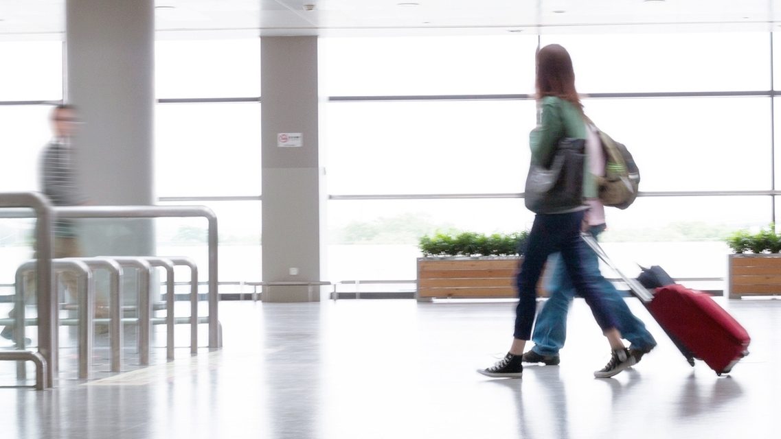 Voyageurs traversant un terminal d'aéroport moderne et lumineux.