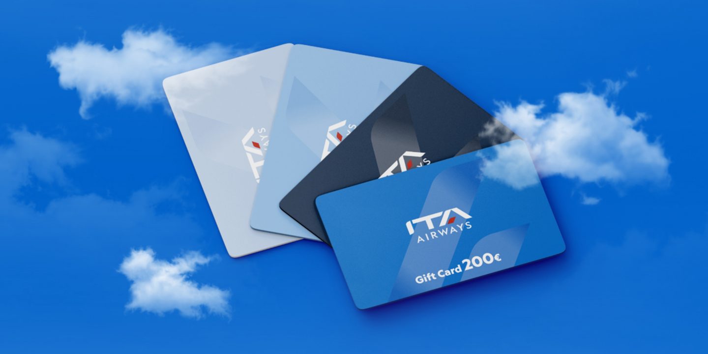 Quattro Gift Card di ITA Airways disposte su uno sfondo blu con nuvole.