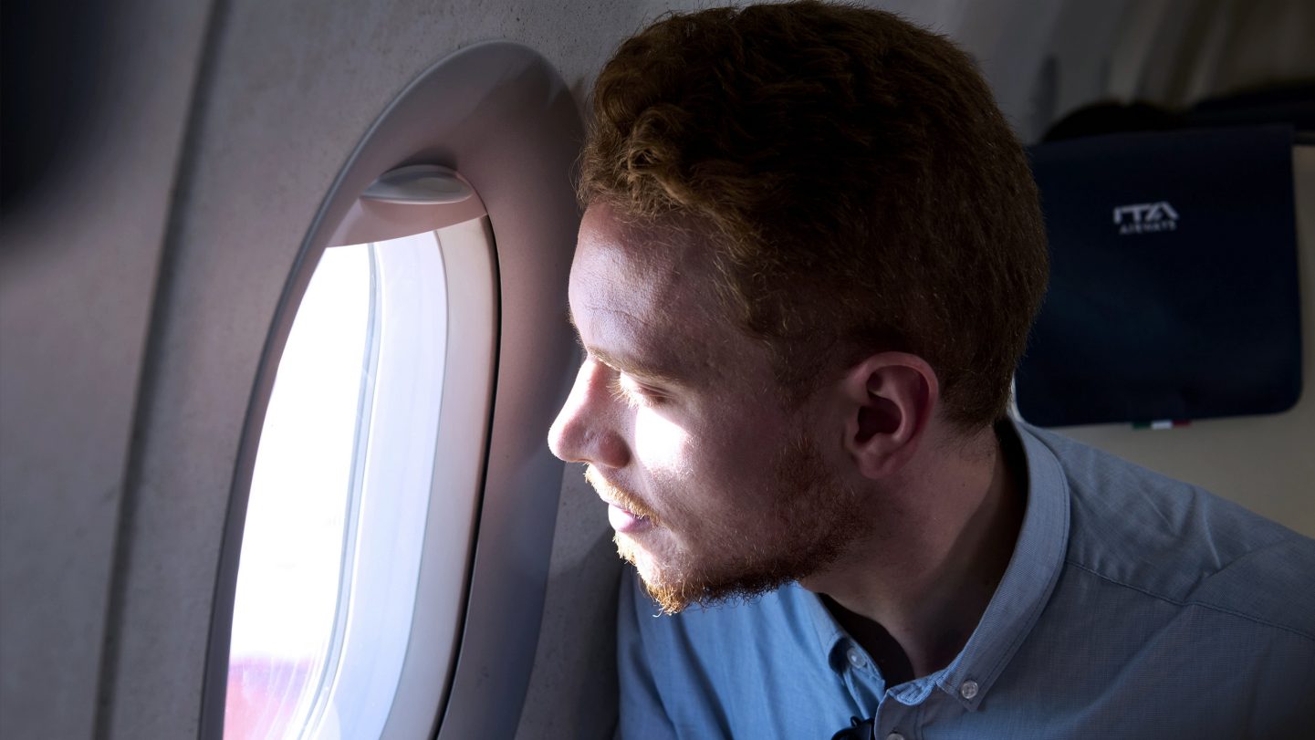 A passenger looking out of the window from a Business Class seat.
