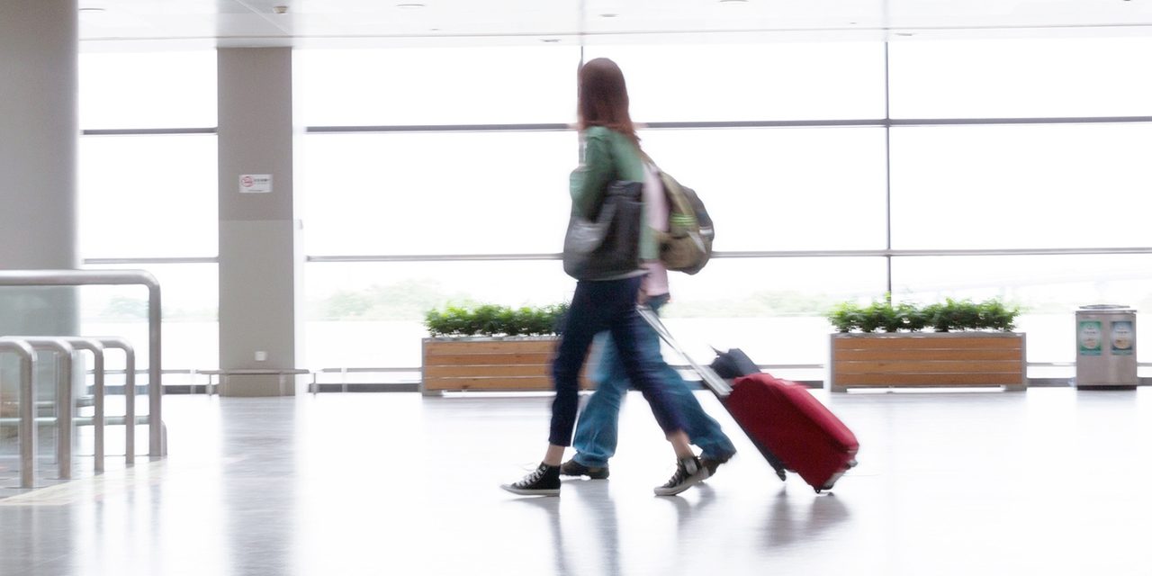 Viajantes caminham por um terminal moderno e iluminado no aeroporto.