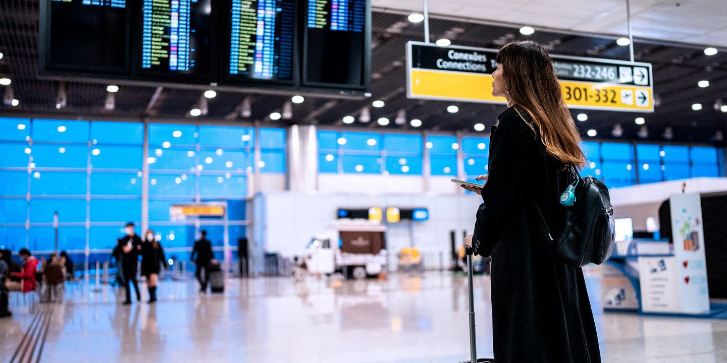 Een vrouw bekijkt vluchttijden op een luchthaven. 