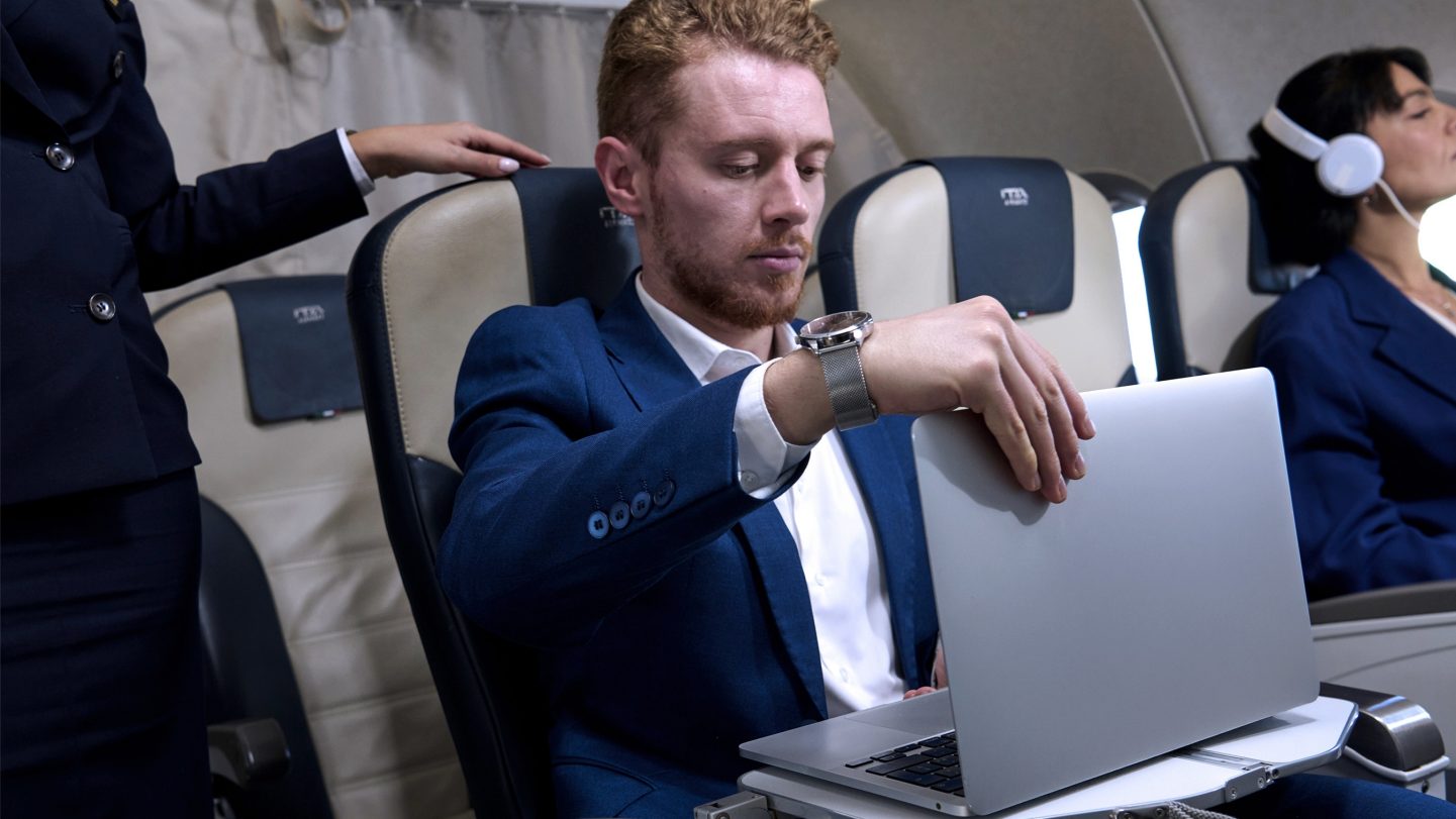 A passenger closes their laptop while seated in Business Class.