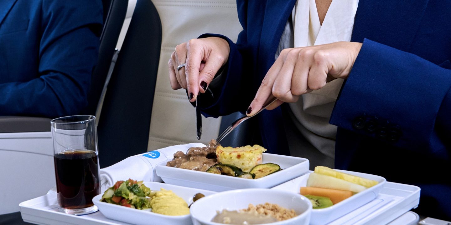 Twee passagiers eten een maaltijd geserveerd in Business-klasse.