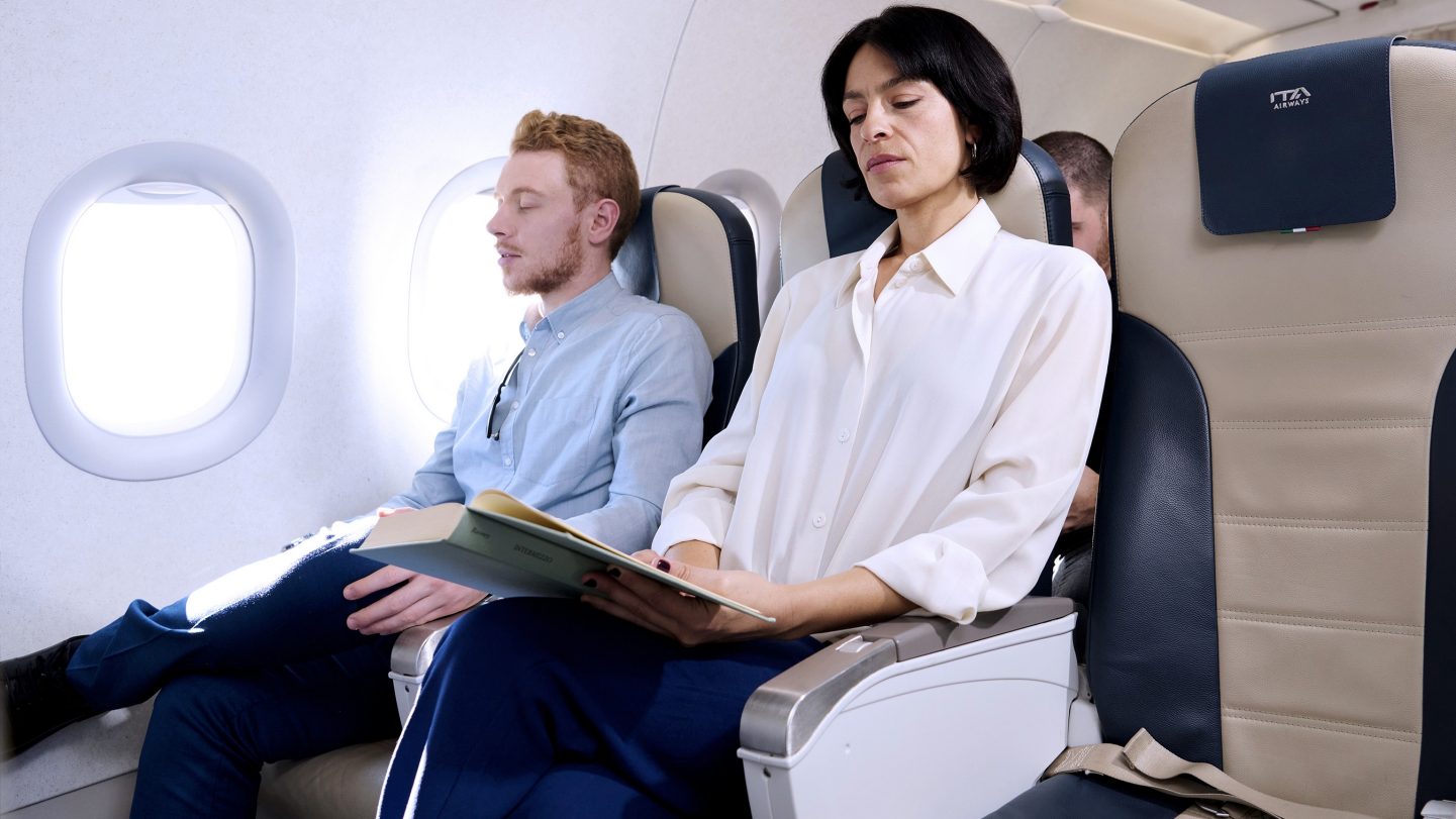 Passengers seated in Business Class, one reading and the other resting.