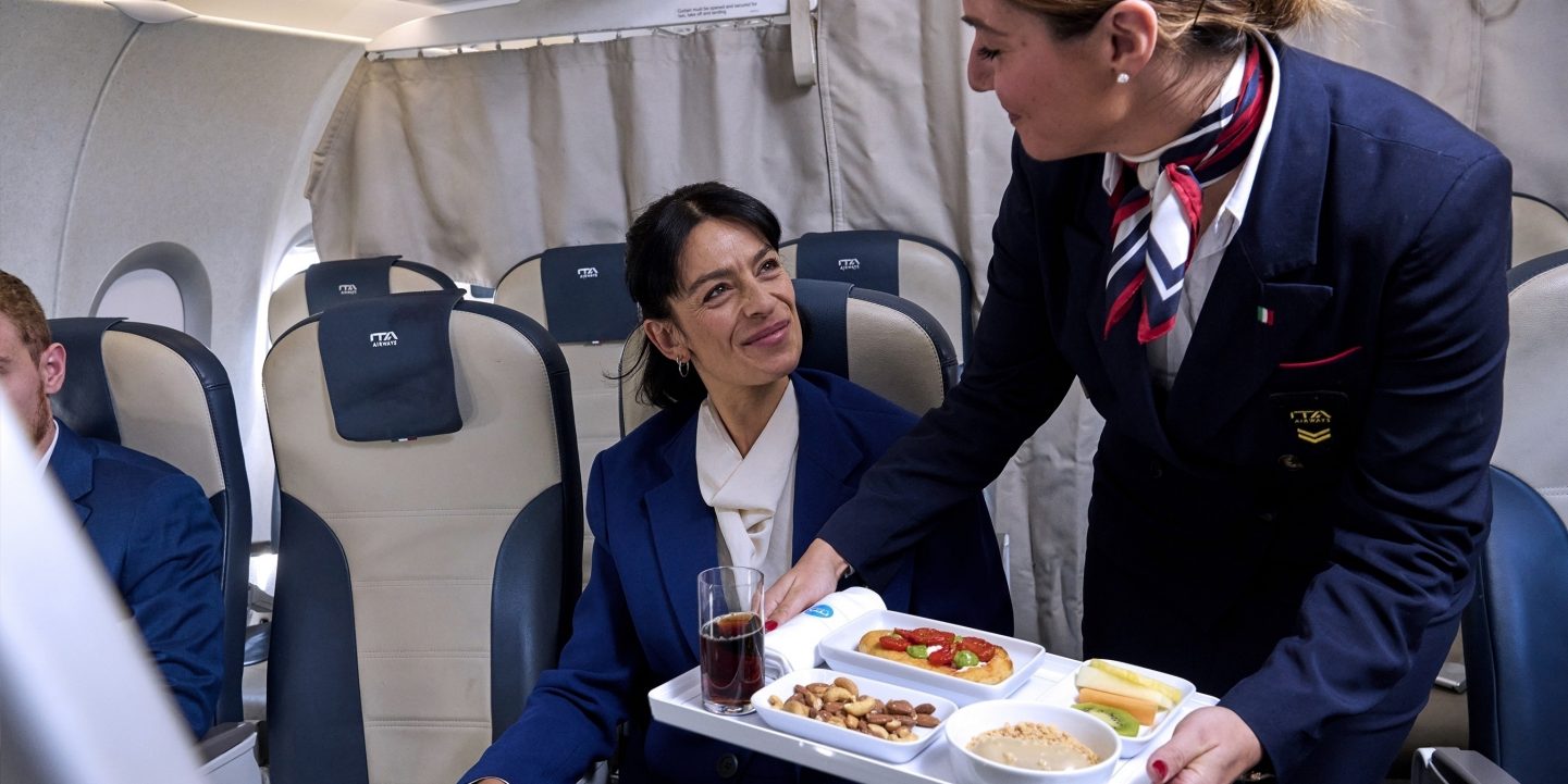 Flight attendant serving a meal for a passenger seated in Business Class.