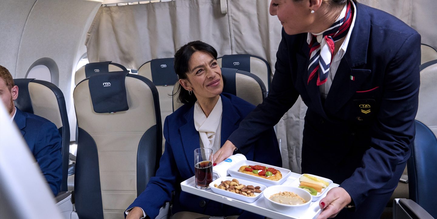 Personnel de cabine servant un repas à un passager assis en classe Business.
