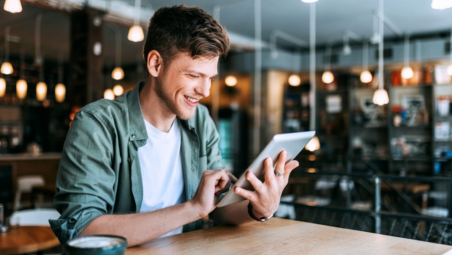 A man seated at a table using a tablet.